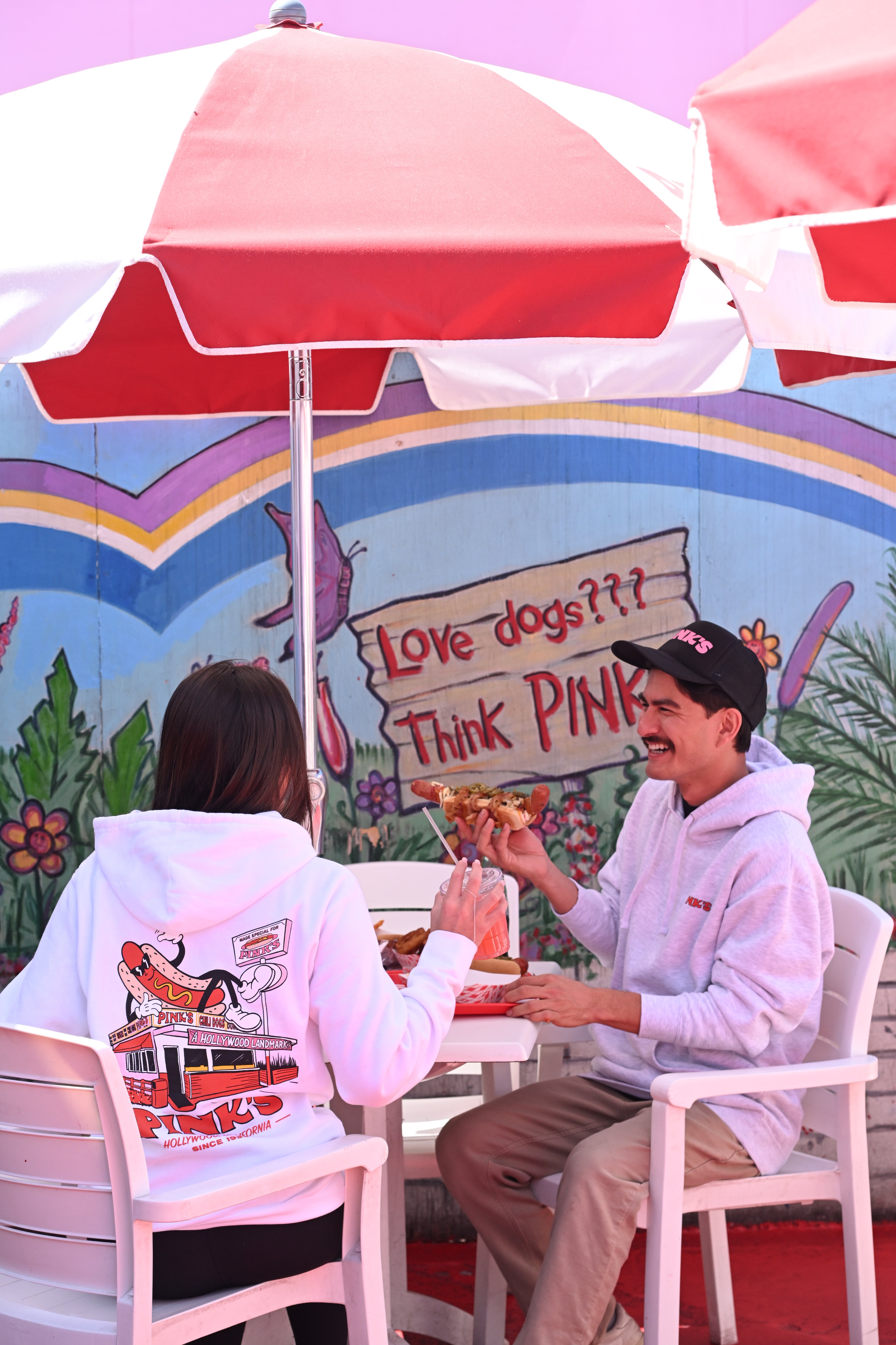 Two people in the new Pink's Street View hoodies sitting on the Pink's Hot Dogs patio